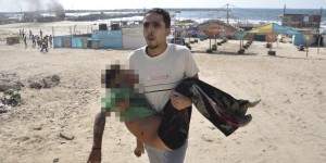 Palestinian man carries the body of a boy, whom medics said was killed by a shell fired by an Israeli naval gunboat, on a beach in Gaza City